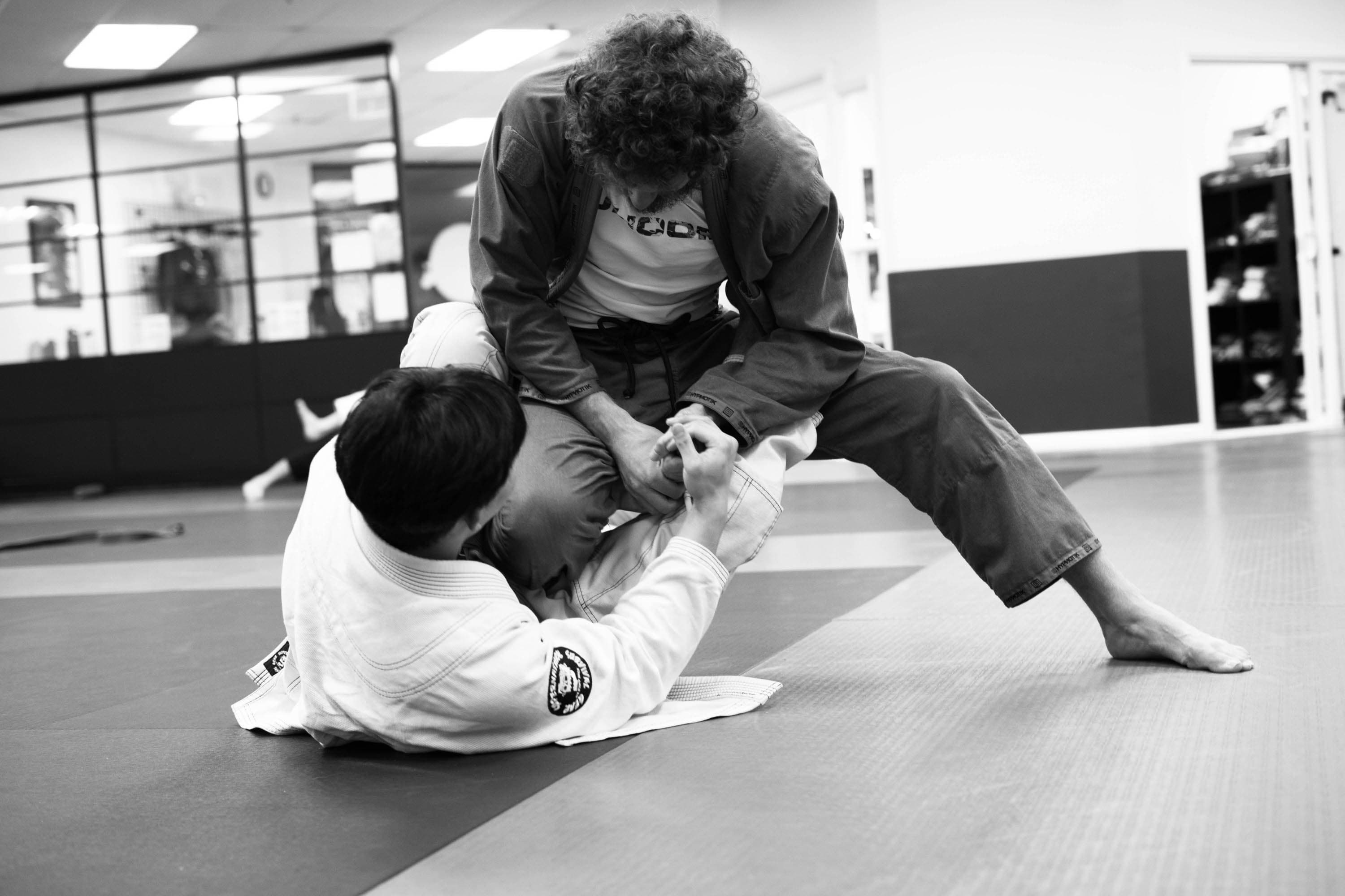 Coach Robbie working with a student during open mat.